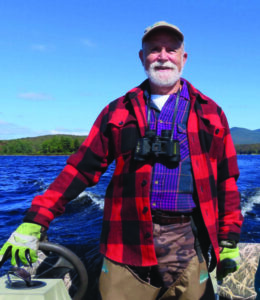 Henry stands at the wheel of his boat as he looks for loons.