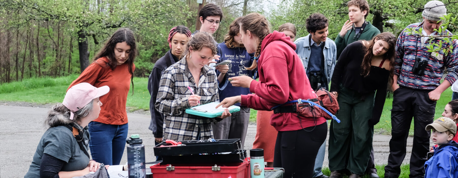 A group of students helps take measurements and data for a bird banding demonstration